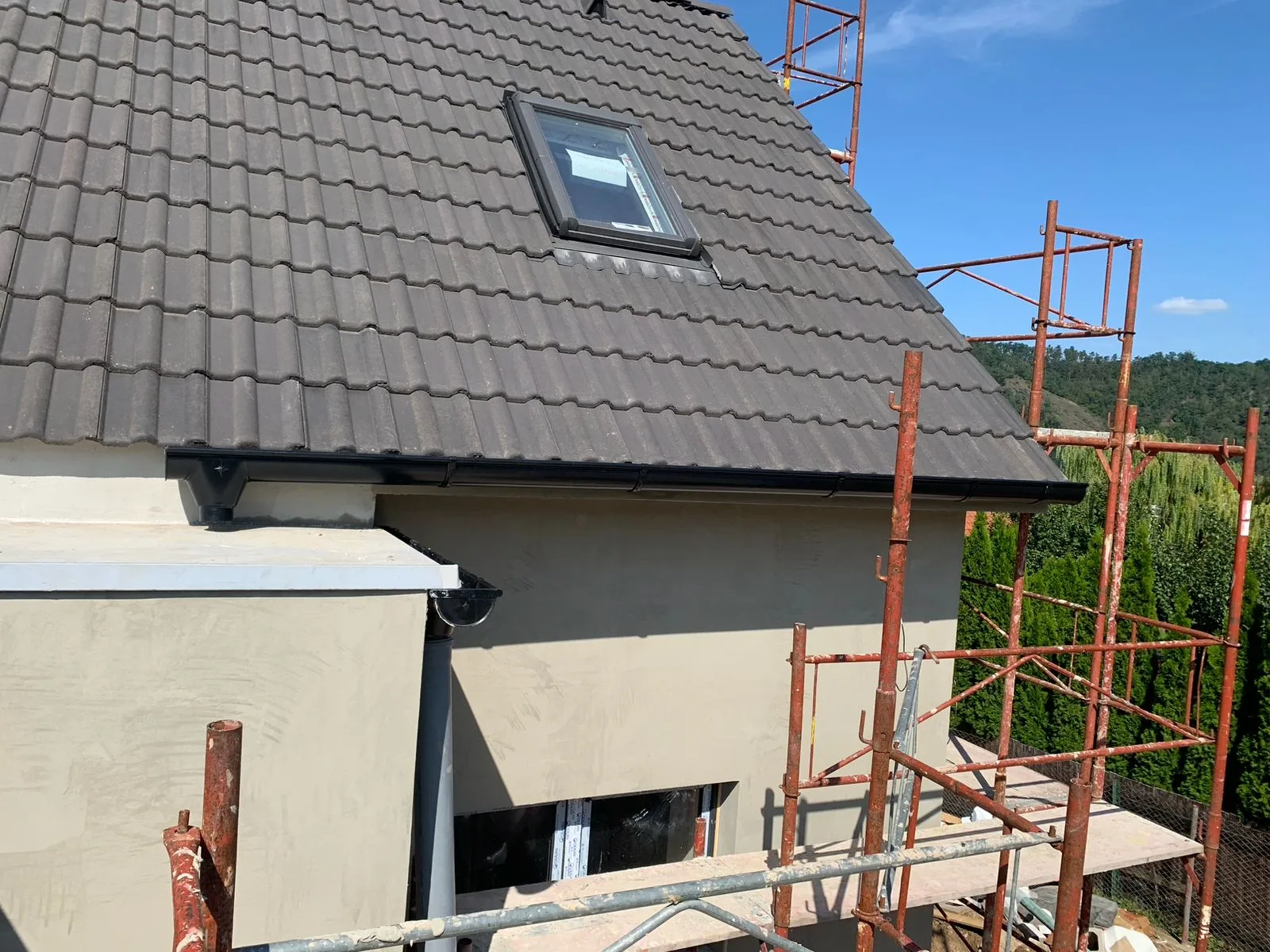 Pohled z ulice na rodinný dům s tmavou betonovou střechou